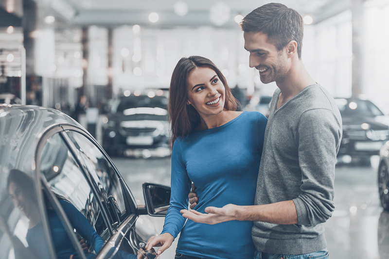 Photo of a couple looking at a car in a showroom